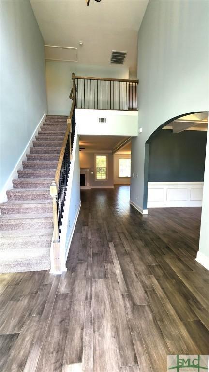 stairway featuring wood-type flooring and a towering ceiling