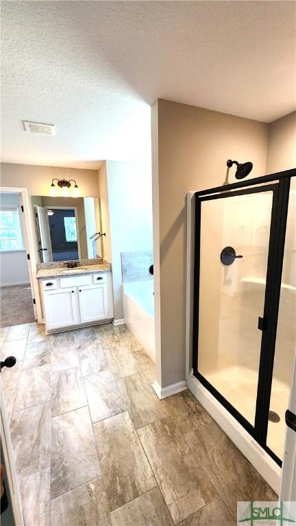 bathroom with plus walk in shower, vanity, and a textured ceiling