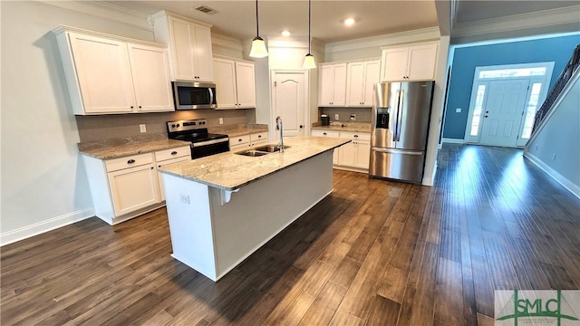 kitchen featuring sink, stainless steel appliances, light stone counters, a center island with sink, and white cabinets