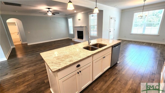 kitchen with light stone countertops, stainless steel dishwasher, sink, hanging light fixtures, and an island with sink