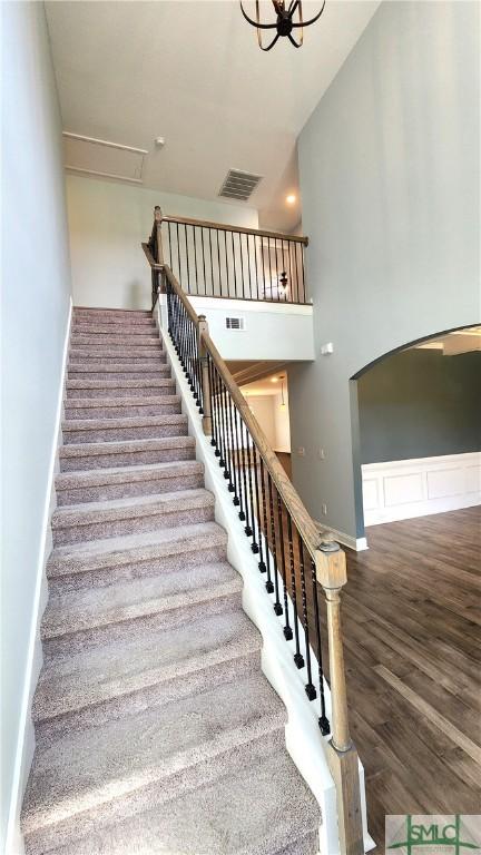 stairway with a notable chandelier and hardwood / wood-style flooring