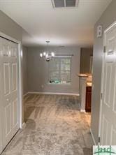 hall featuring carpet floors and a notable chandelier