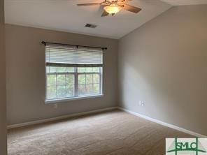 spare room with carpet floors, vaulted ceiling, and ceiling fan