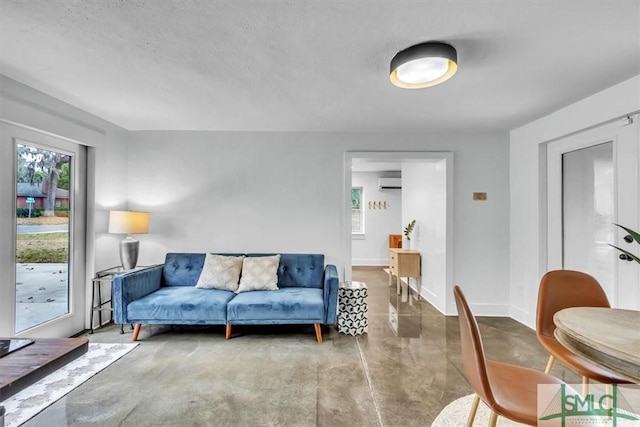 living room with a wall unit AC, concrete flooring, and a textured ceiling