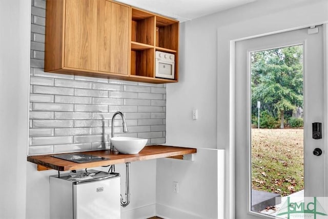 kitchen with wood counters, backsplash, fridge, and sink