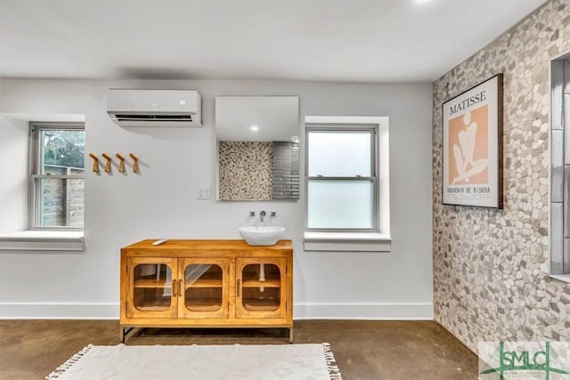 interior details featuring sink, a wall unit AC, and concrete floors