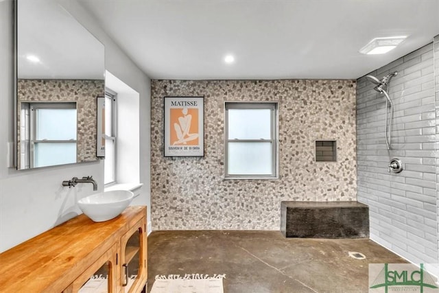 bathroom featuring vanity, a shower, concrete floors, and a healthy amount of sunlight