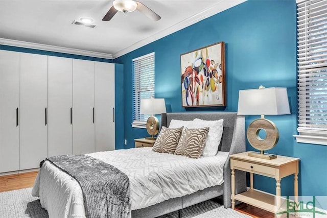 bedroom with a closet, ceiling fan, crown molding, and wood-type flooring