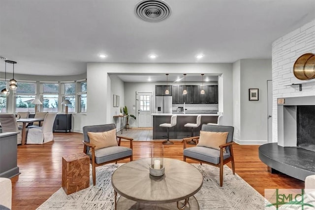 living room with hardwood / wood-style flooring, a healthy amount of sunlight, and a stone fireplace