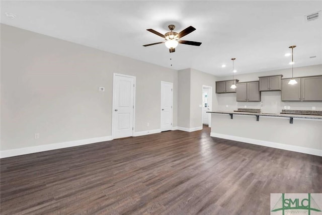 unfurnished living room with ceiling fan and dark wood-type flooring