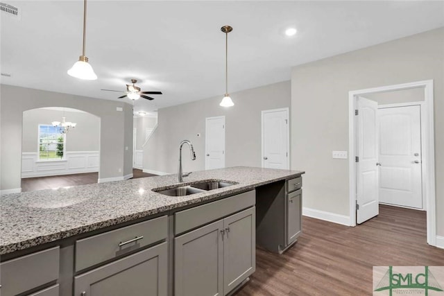 kitchen featuring gray cabinetry, light stone countertops, sink, hanging light fixtures, and ceiling fan with notable chandelier