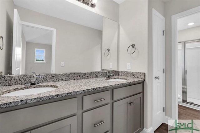 bathroom featuring wood-type flooring, vanity, toilet, and a shower with shower door