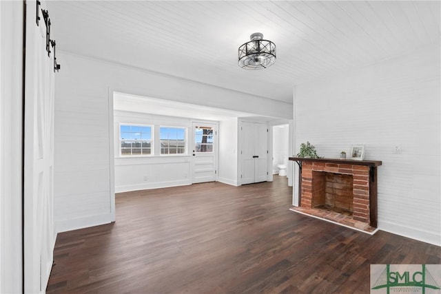 unfurnished living room with a chandelier, dark hardwood / wood-style flooring, and a barn door