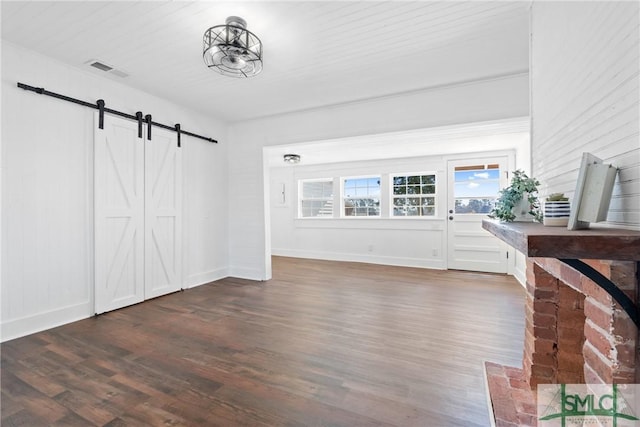 unfurnished living room featuring dark hardwood / wood-style floors and a barn door