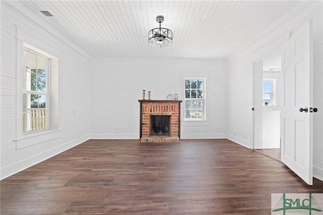 unfurnished living room with dark hardwood / wood-style flooring, a brick fireplace, and a healthy amount of sunlight