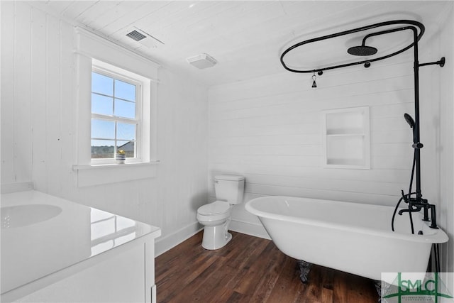 bathroom with hardwood / wood-style floors, vanity, wood walls, toilet, and a tub to relax in