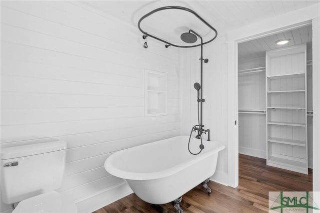 bathroom with toilet, a bath, and wood-type flooring