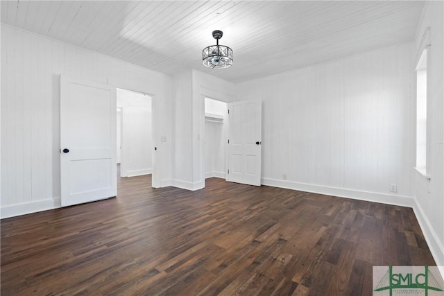 empty room featuring dark wood-type flooring and an inviting chandelier