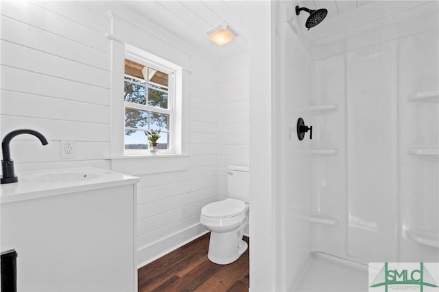 bathroom featuring a shower, hardwood / wood-style floors, vanity, and wooden walls