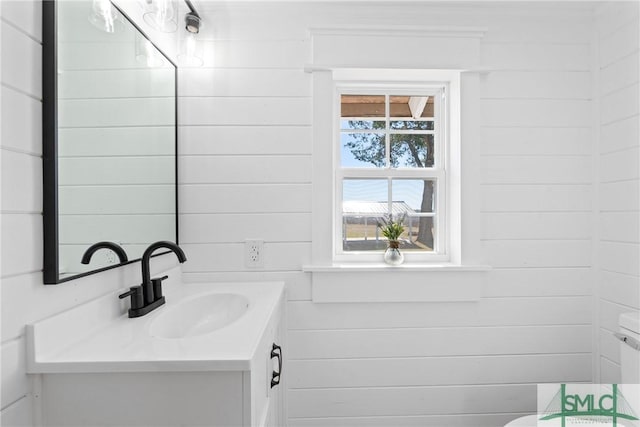 bathroom with vanity, toilet, and wooden walls