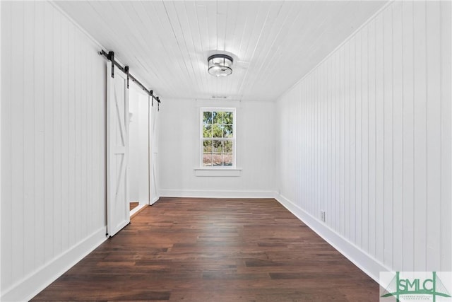 hallway with a barn door, wood walls, and dark hardwood / wood-style floors