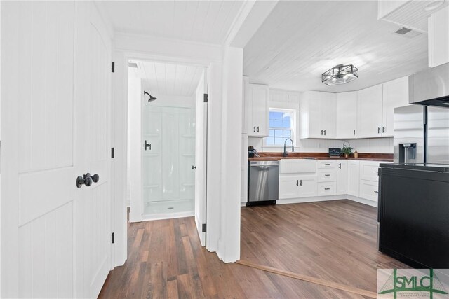 kitchen with appliances with stainless steel finishes, dark wood-type flooring, sink, butcher block countertops, and white cabinetry