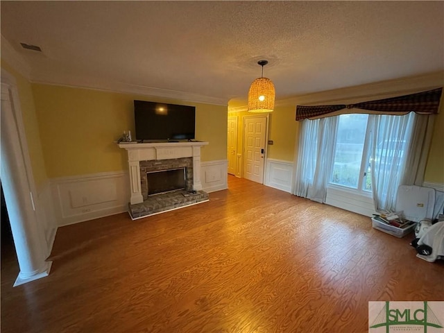 unfurnished living room with a fireplace, wood-type flooring, a textured ceiling, and ornamental molding