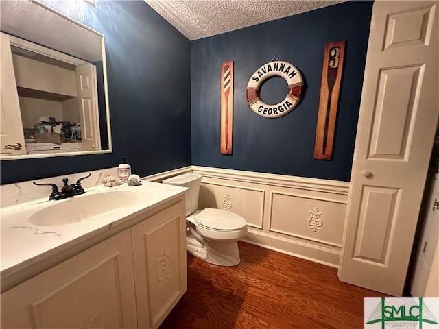 bathroom with hardwood / wood-style floors, vanity, toilet, and a textured ceiling