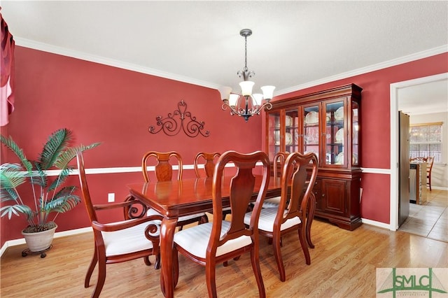 dining space featuring an inviting chandelier, ornamental molding, and light wood-type flooring