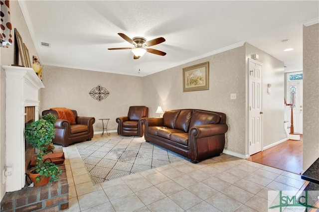 tiled living room with a brick fireplace, ceiling fan, and ornamental molding