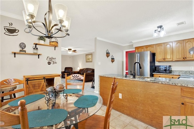 kitchen with sink, light stone countertops, light tile patterned floors, ornamental molding, and stainless steel refrigerator