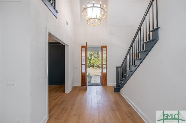 entrance foyer featuring a towering ceiling, a chandelier, and light wood-type flooring