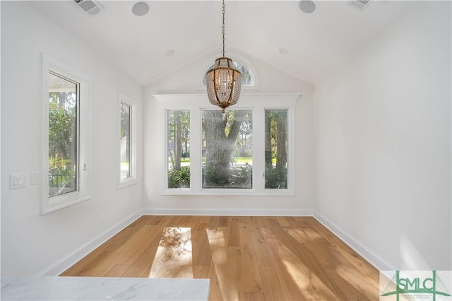 unfurnished dining area with wood-type flooring, lofted ceiling, and a notable chandelier