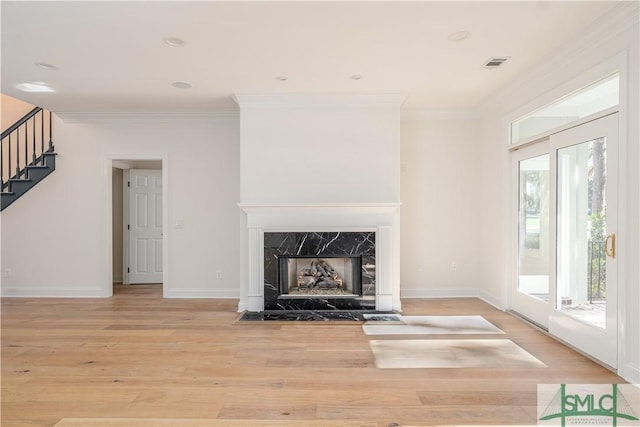 unfurnished living room featuring a fireplace, light wood-type flooring, and ornamental molding