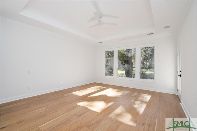 spare room featuring ceiling fan, ornamental molding, light hardwood / wood-style flooring, and a tray ceiling