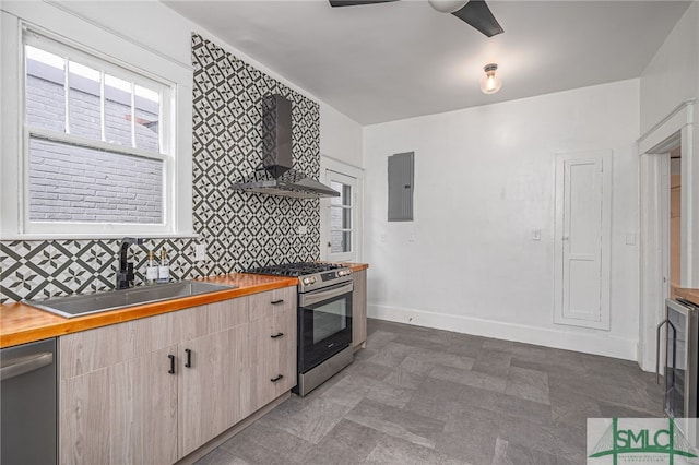 kitchen with sink, wall chimney exhaust hood, stainless steel appliances, butcher block countertops, and electric panel