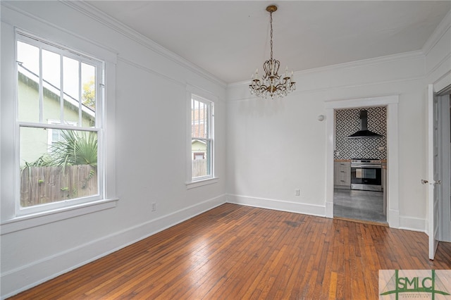 unfurnished dining area featuring a notable chandelier, wood-type flooring, and crown molding