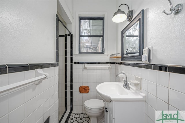 bathroom with vanity, tile patterned floors, toilet, tile walls, and walk in shower