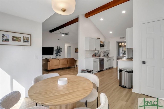 dining room with ceiling fan, sink, lofted ceiling with beams, and light wood-type flooring