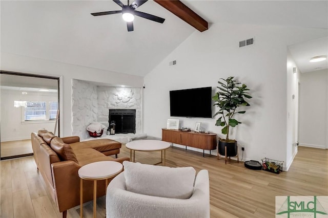 living room featuring a fireplace, ceiling fan, high vaulted ceiling, light hardwood / wood-style flooring, and beamed ceiling