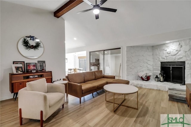 living room with vaulted ceiling with beams, light hardwood / wood-style floors, a stone fireplace, and ceiling fan