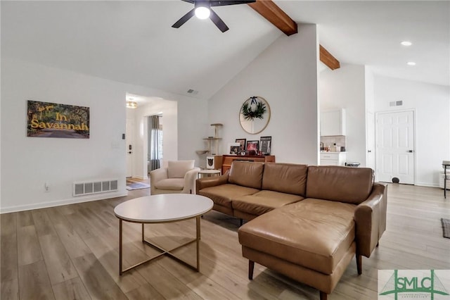 living room with ceiling fan, beamed ceiling, light hardwood / wood-style floors, and high vaulted ceiling