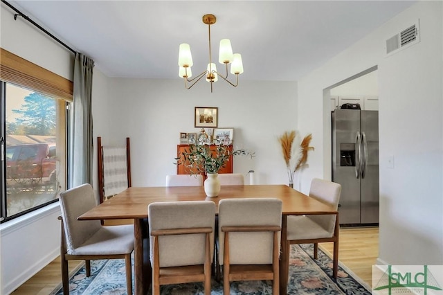 dining space with light hardwood / wood-style flooring and an inviting chandelier