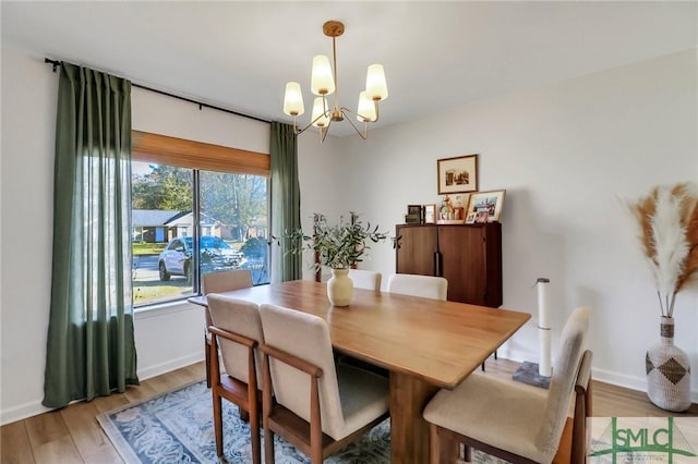 dining space with light wood-type flooring and an inviting chandelier