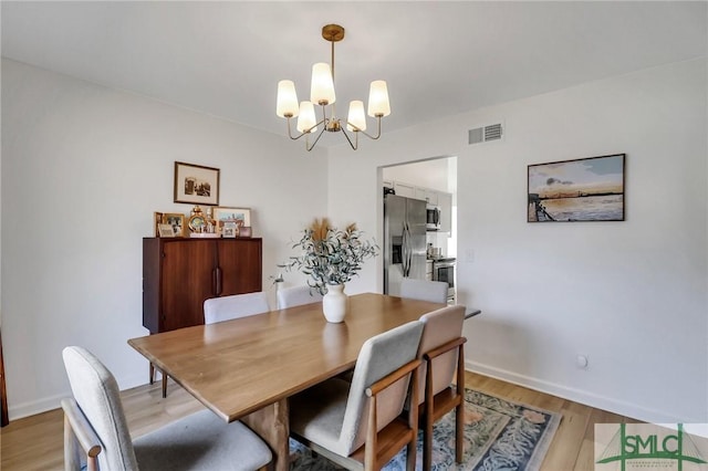 dining room with light wood-type flooring and a notable chandelier