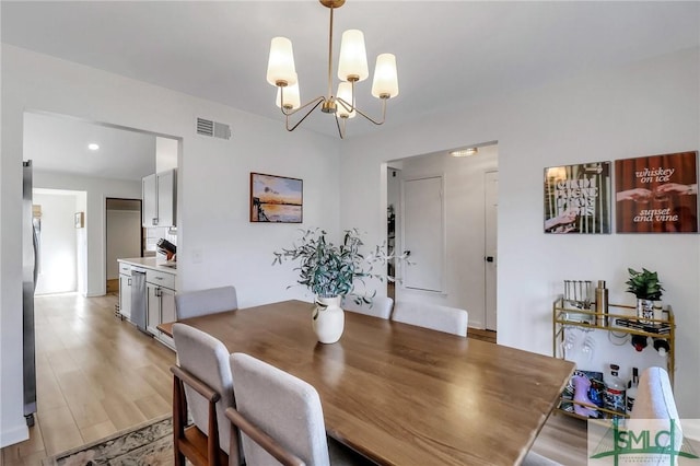 dining space featuring light hardwood / wood-style flooring and a chandelier