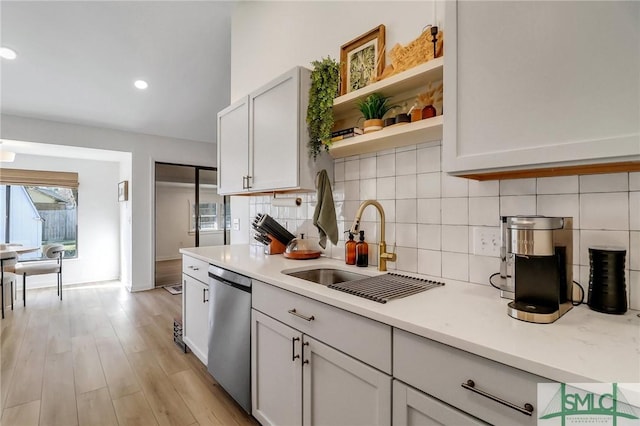 kitchen with decorative backsplash, stainless steel dishwasher, sink, light hardwood / wood-style flooring, and white cabinets