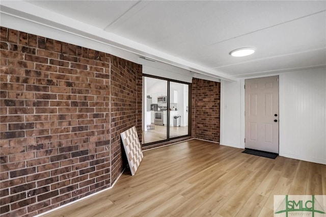 interior space with light hardwood / wood-style floors and brick wall