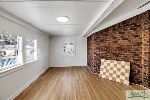 interior space with light wood-type flooring and brick wall