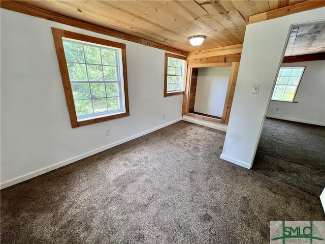 unfurnished bedroom with dark carpet, multiple windows, and wooden ceiling